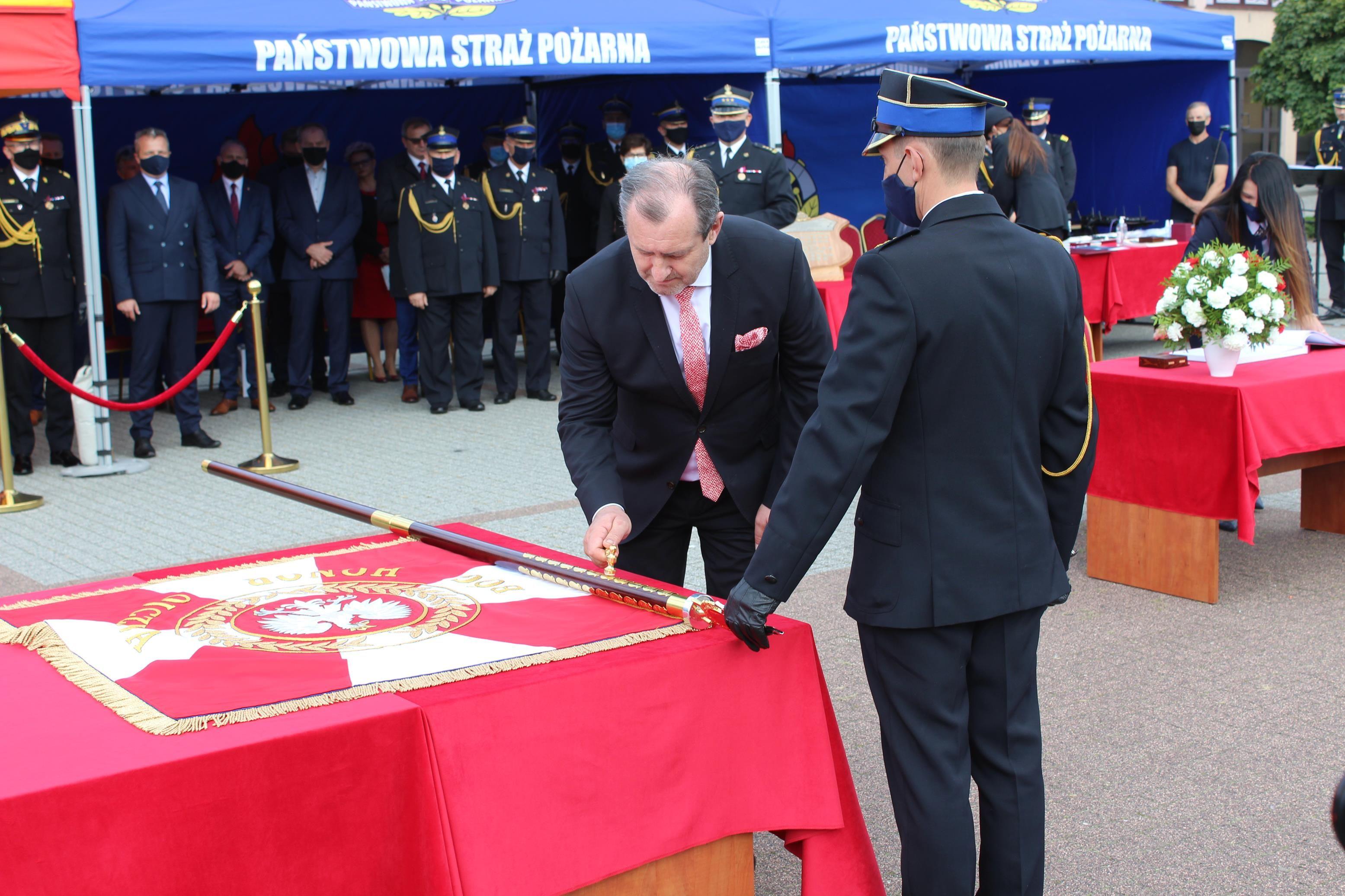 Burmistrz Paweł Banasik wbija symboliczny gwóźdź w drzewiec sztandaru - kliknięcie spowoduje powiększenie obrazka